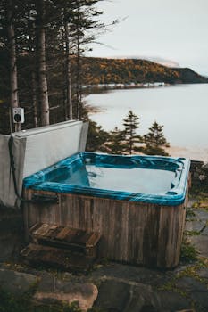 A cozy wooden hot tub in a forest setting with a serene lake view. Perfect for relaxation.